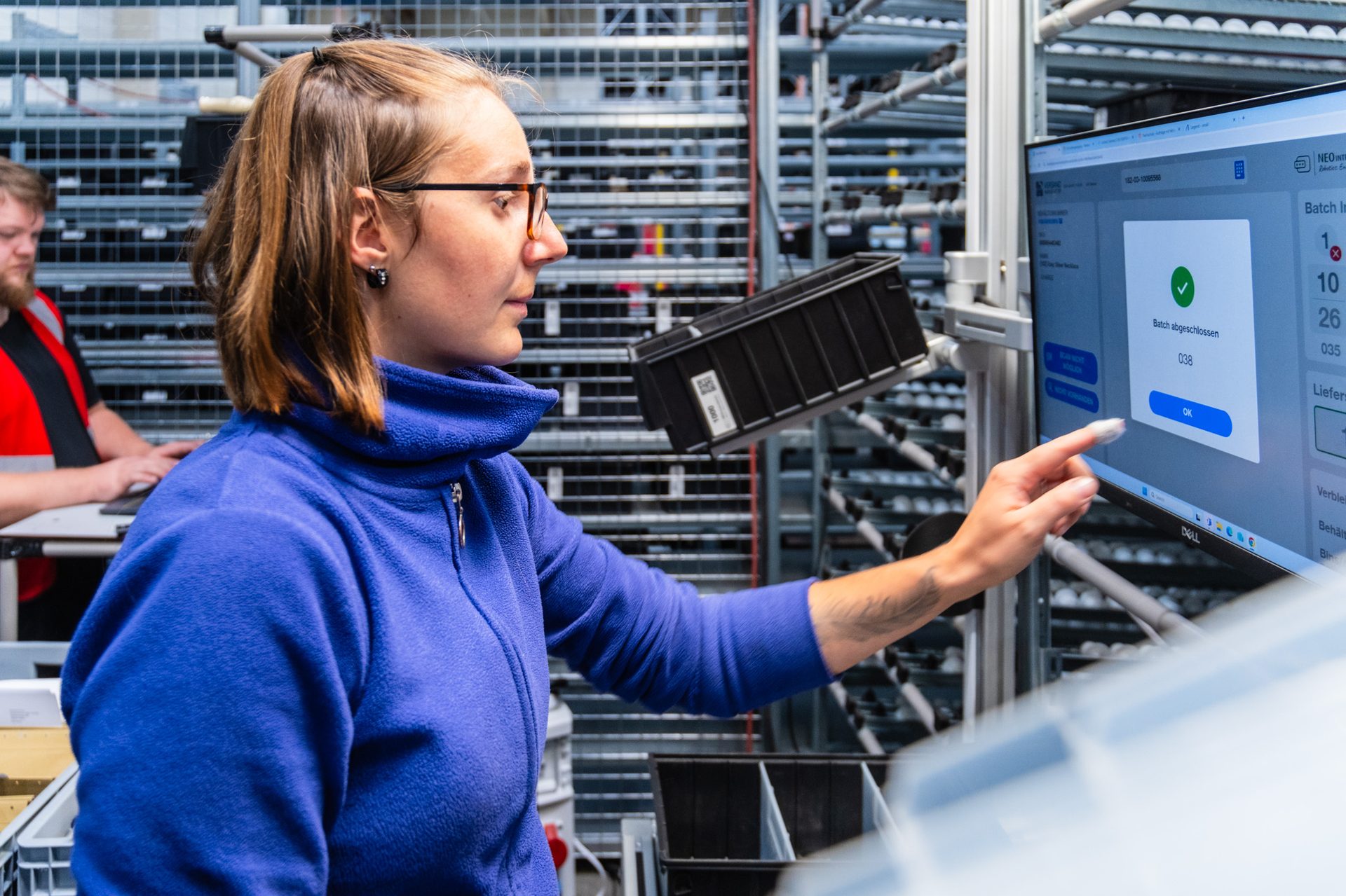 Operator bedient NEO:os Touchscreen — Erfolgsanzeige bei der Kommissionierung