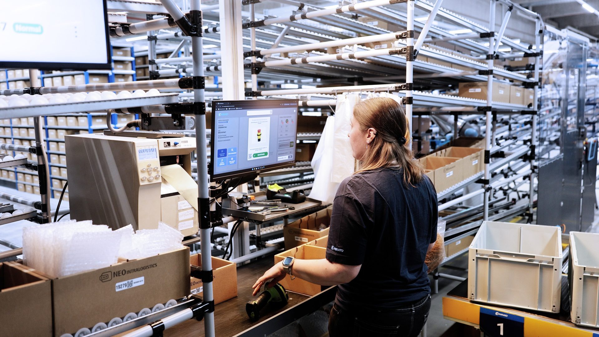 Operator am Ware-zur-Person-Arbeitsplatz mit NEO:os Monitor